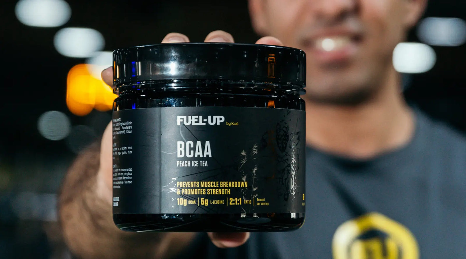 Man holding a tub of BCAAs in the gym