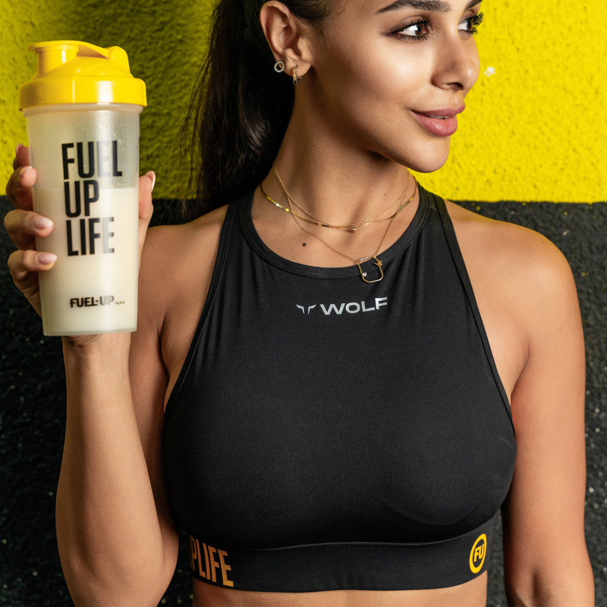 Woman in sports bra holding supplement shaker with Vanilla protein shake