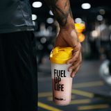 Man holding a protein shaker with strawberry protein shake in the gym