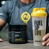 Man in the gym holding a shaker with BCAAs next to a tub in the gym