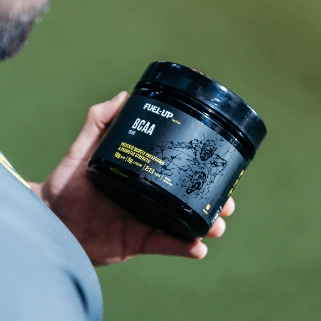 Man holding a tub of BCAA powder in the gym