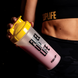 Woman holding a protein shaker with strawberry protein shake inside