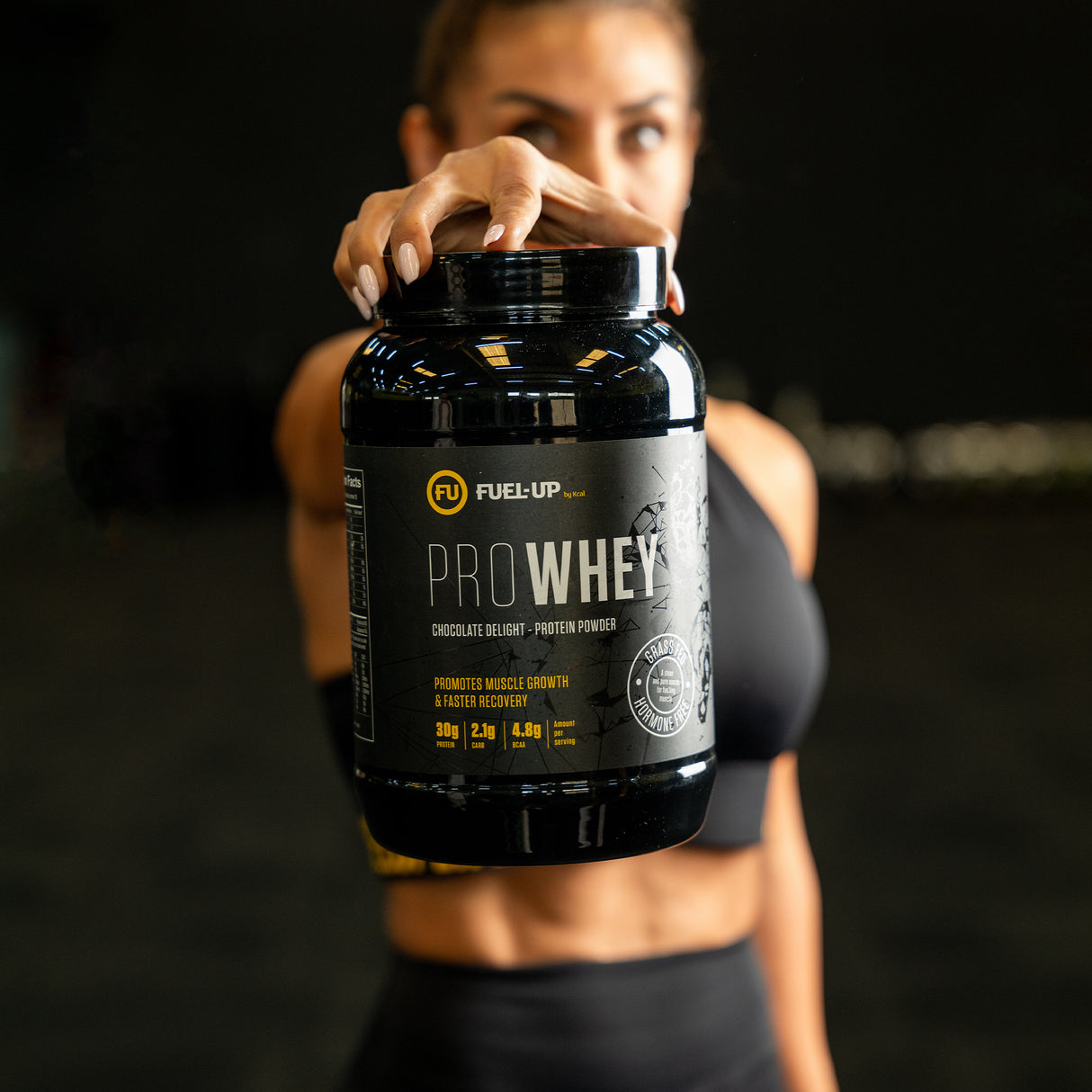 Athletic woman holding a 2lb container of chocolate delight protein powder