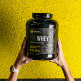 Woman holding a 5 lb container of chocolate flavoured whey protein powder